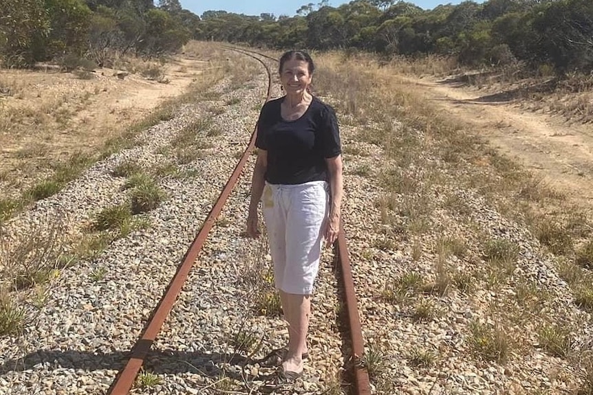 A woman standing on a rail line.