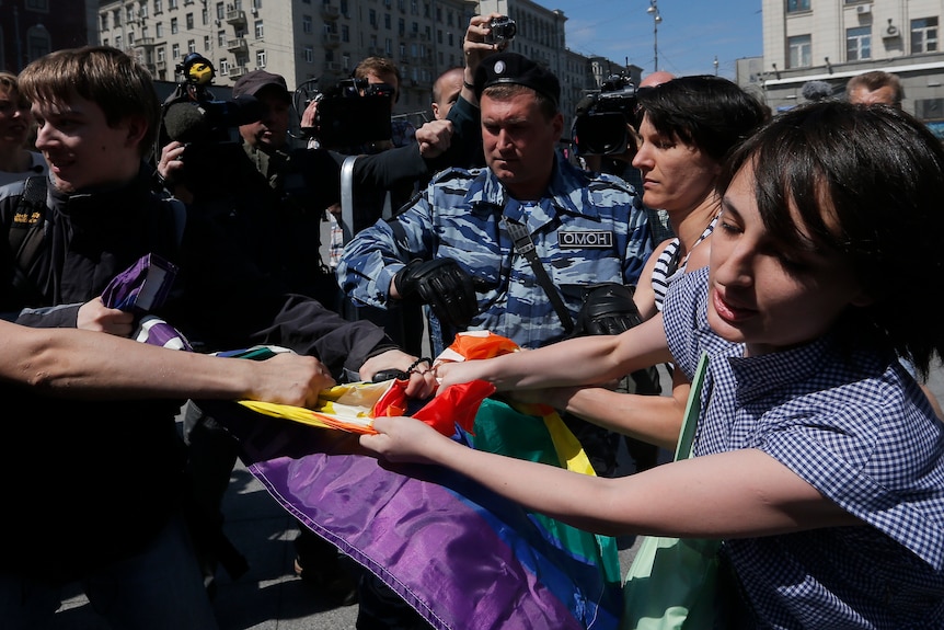 A man tries to stop gay rights activists holding a flag during a protest in Moscow