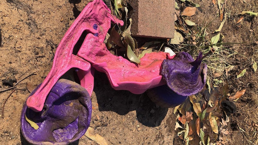 Melted child's pink and purple plastic bike at a property at Mount Larcom after bushfires.
