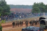 Guards patrol a land border from behind barbed wire