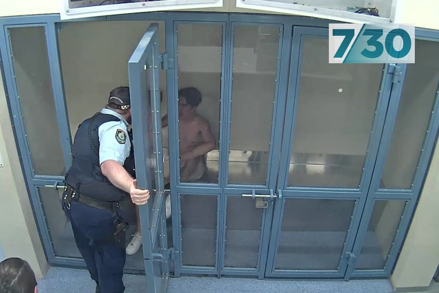 A police officer speaks to a man in cell.