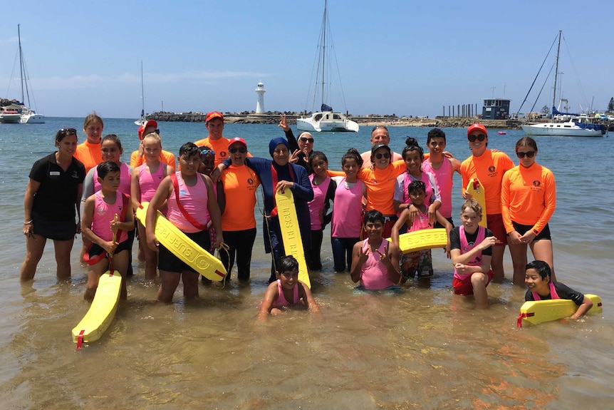 Group of children stand knee deep in water at a beach