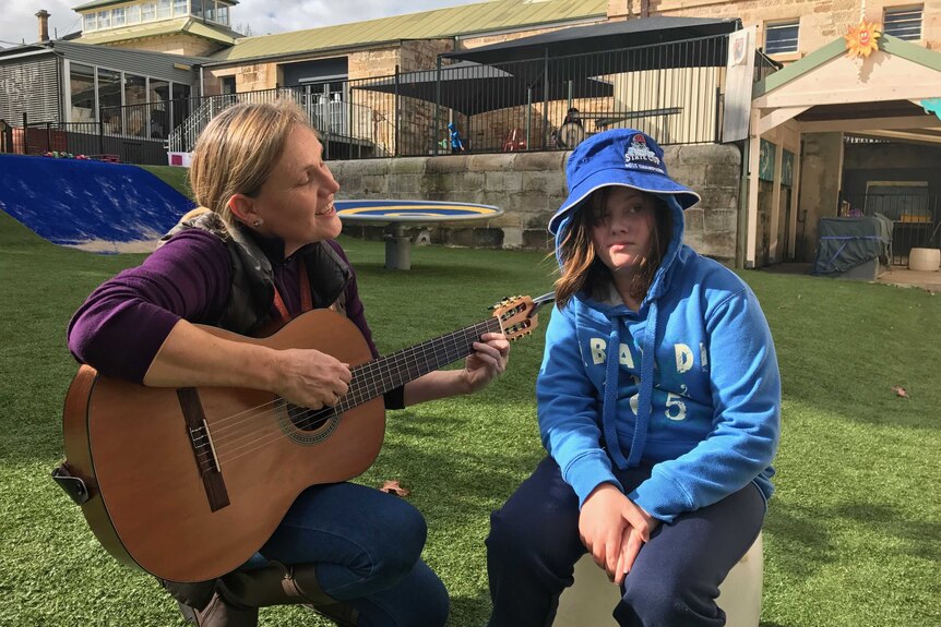 12 year old Shelby listens to her teacher playing the guitar at Giant Steps school in Sydney