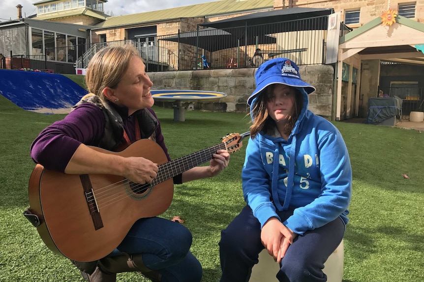 12 year old Shelby listens to her teacher playing the guitar at Giant Steps school in Sydney