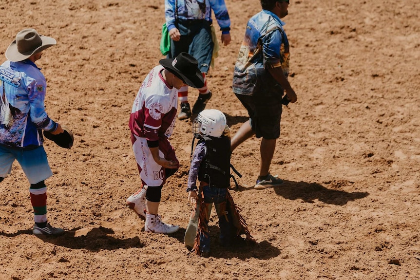 Bullfighter in rodeo arena high-fiving young boy in riding gear