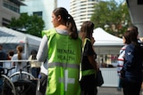 A person wearing a high-vis vest with 'mental health' written on the back stands on a street.