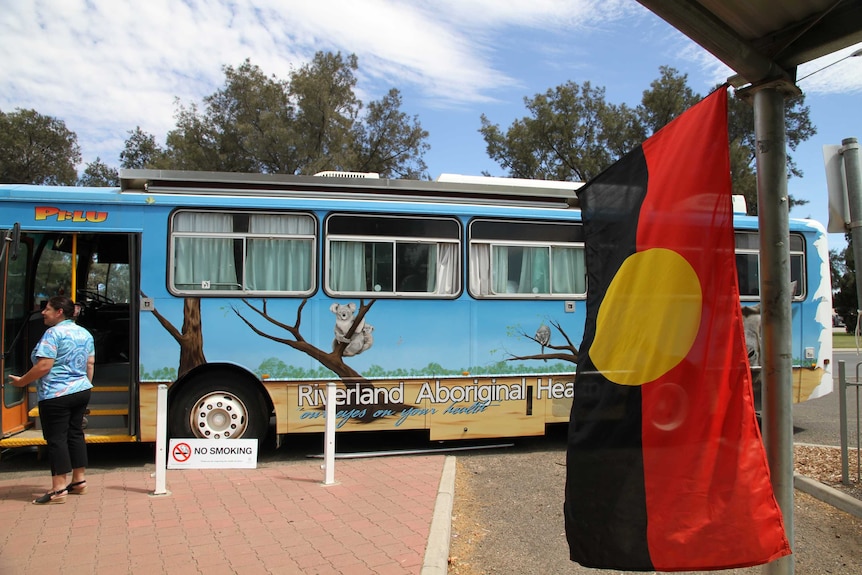 An Aboriginal flag hanging from a building, with the health bus in the background.