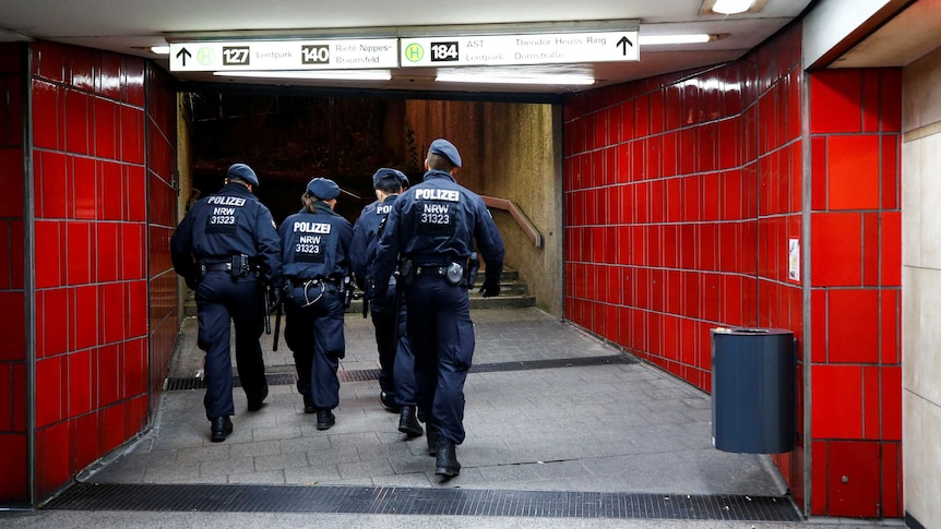 German police officers walk through an underground station.