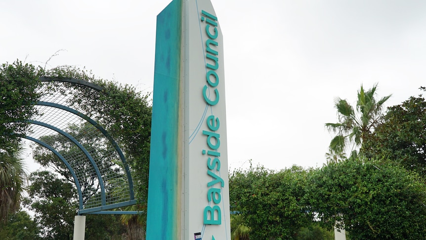 An obelisk bearing the lettering "Bayside Council" in a small park.