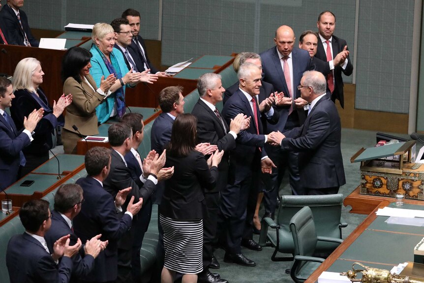 Scott Morrison shakes hands with Malcolm Turnbull amid standing MPs