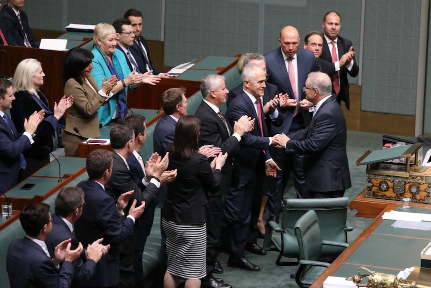 Scott Morrison shakes hands with Malcolm Turnbull amid standing MPs