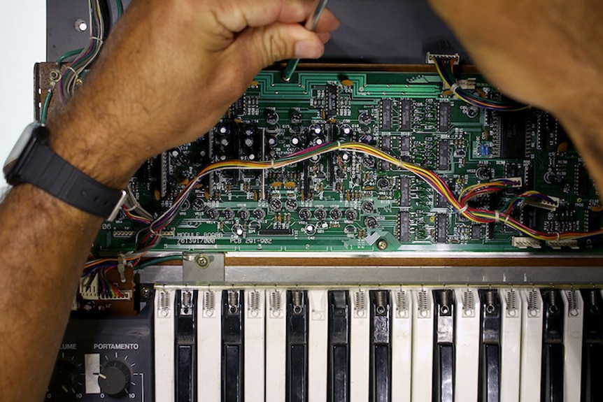 Circuit boards opened to see inside a vintage synthesizer.
