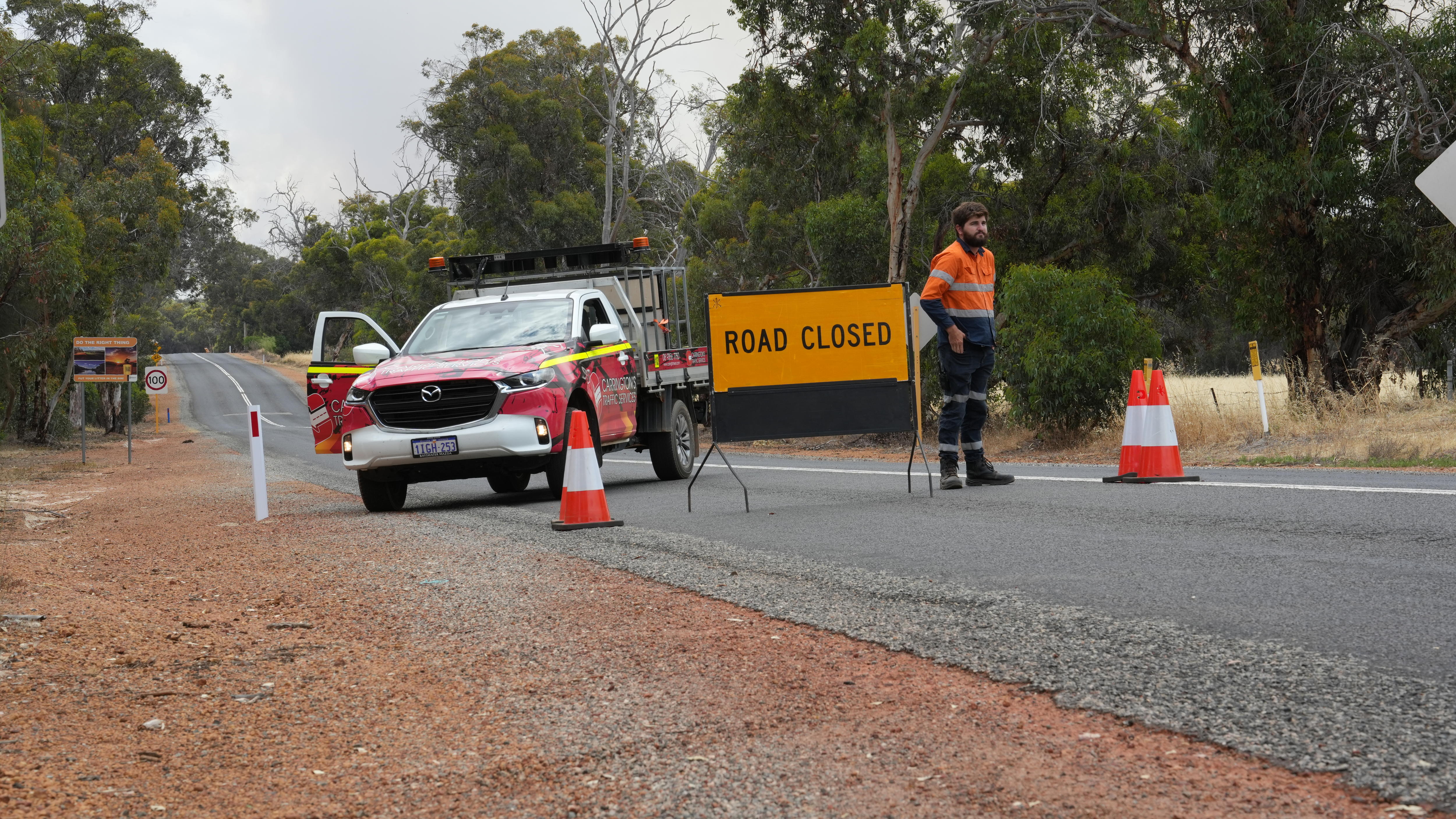 Un hombre claramente visible se encuentra frente a una señal de cierre de carretera.