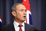 A side view of Roger Cook speaking at a press conference