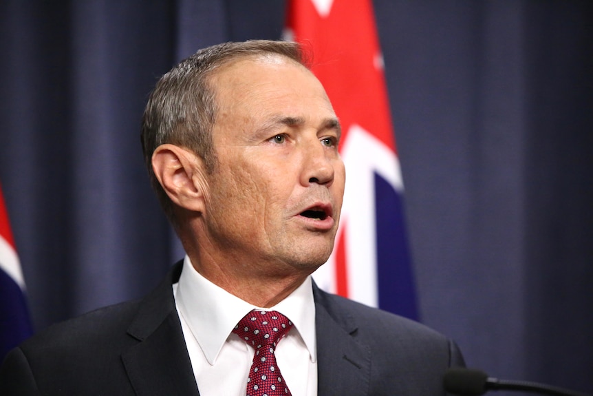 A side view of Roger Cook speaking at a press conference