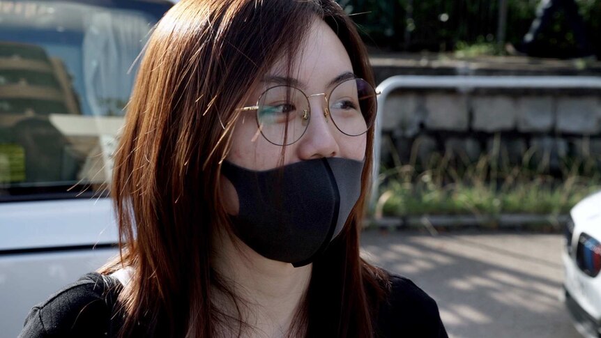 A close photo of Caitlyn who is wearing a black shirt, face mask and glasses.