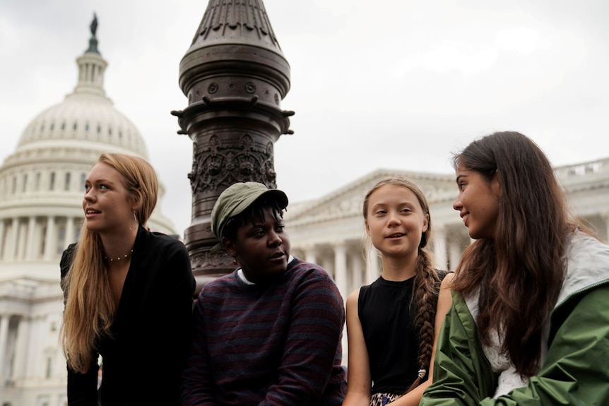 Greta Thunberg sits with three other young people in front of the Us Capitol in Washington.