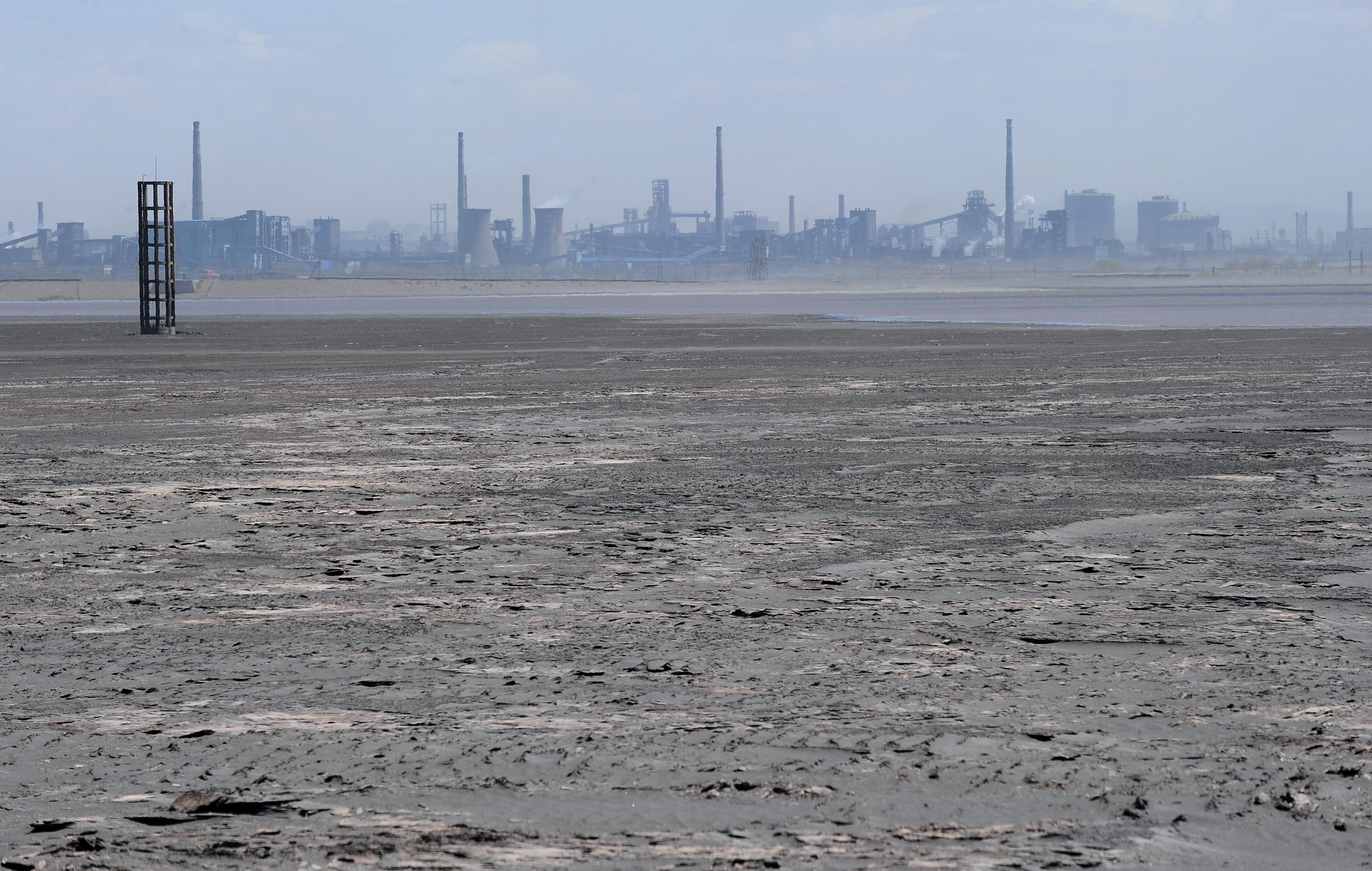 A black sludgy expanse surrounds an industrial city.