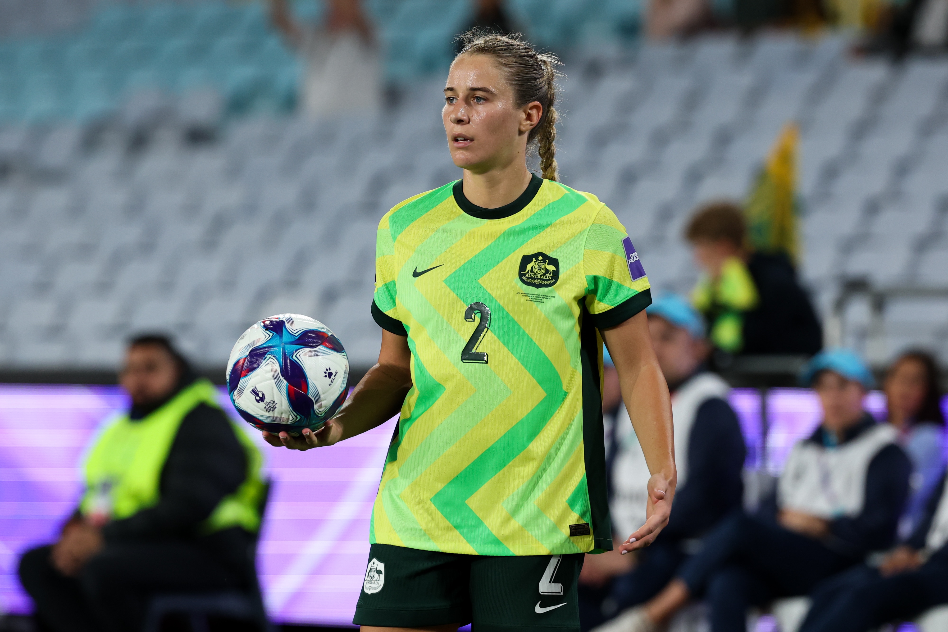 A soccer player in green and gold holds a ball