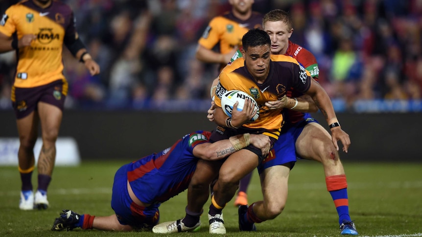 Joe Ofahengaue (centre) of the Broncos is tackled by Jack Stockwell (right) and Kade Snowden