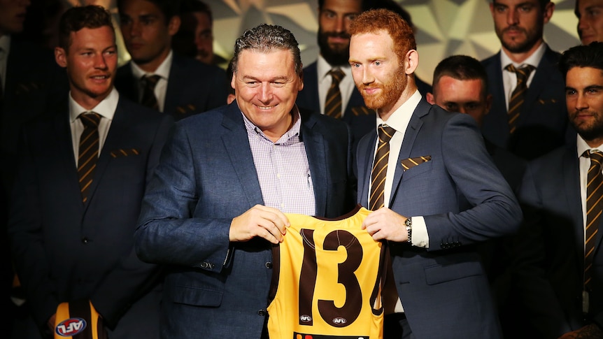 Conor Glass of the Hawks accepts his jumper from Paul Dear (L) during the Hawthorn Hawks AFL 2019 season launch.