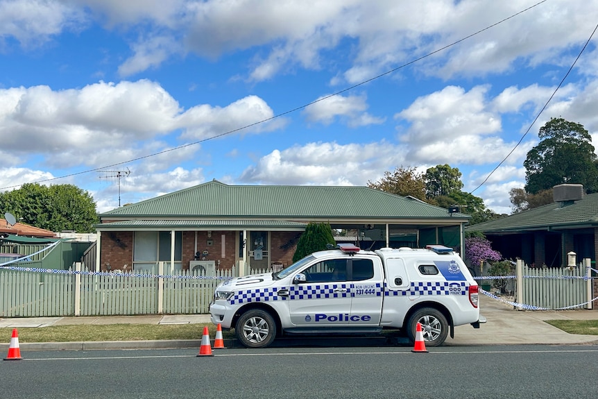 A police car parked out the front of a single-storey suburban house.