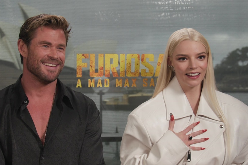 Actors Chris Hemsworth and Anya Taylor-Joy smile. Backdrop shows film title 'Furiosa: A Mad Max Saga'.