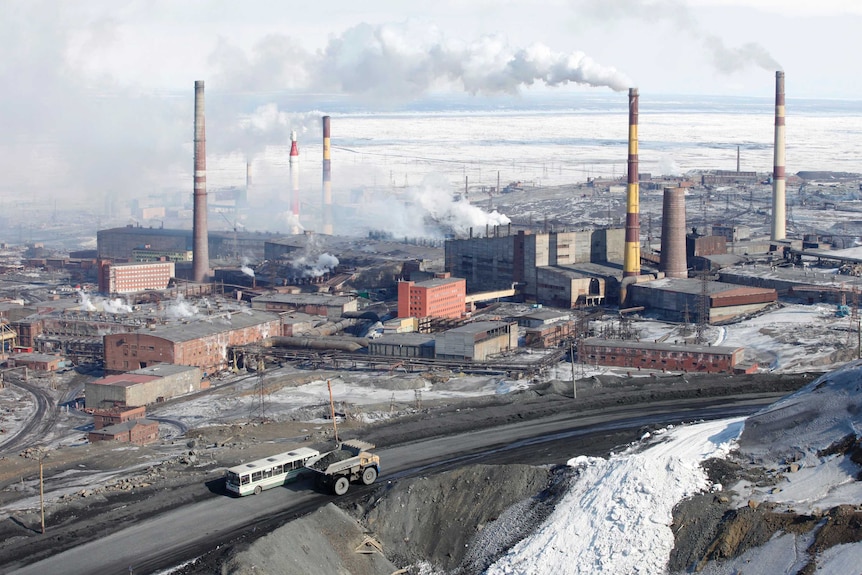 Smoke rises from chimneys of Norilsk Nickel's nickel plant which is pictured surrounded by snow.