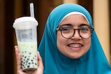 Girl holding a plastic cup of bubble tea.