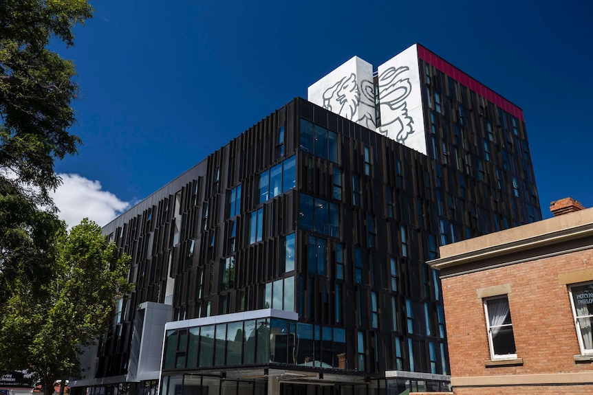 A tall building of apartments with the University of Tasmania's lion logo stamped on the top