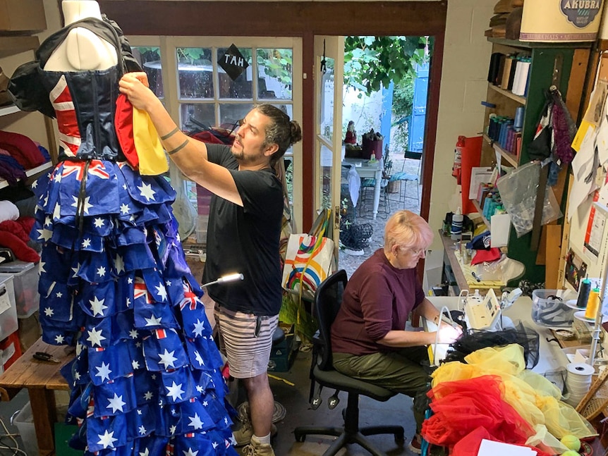 Two people are actively sewing in a garden studio