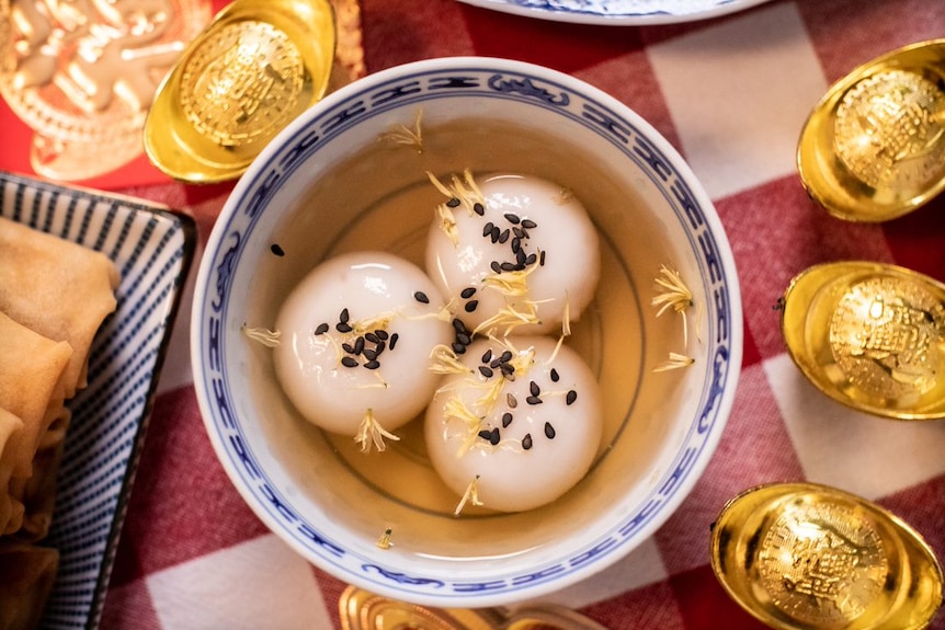 Lunar New Year sweet rice dumplings in a bowl with sweet soup on a festive table setting.