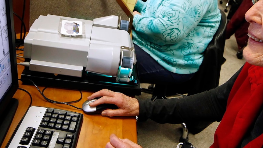 An elderly woman works on a computer.