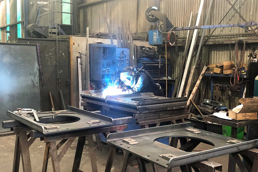 A welder works on a piece of metal.