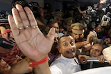 Kuldeep Singh Sengar puts his hand up and is surrounded by media and police as he tries to get into a car.