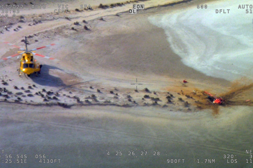 An aerial image of a helicopter at a crash site next to a lake