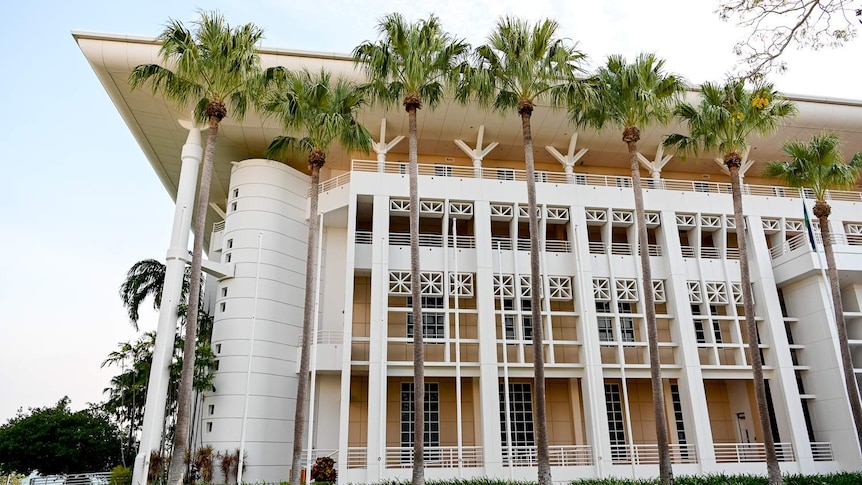 A grand looking building is surrounded by palm trees.