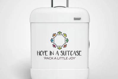 White suitcase with 'hope in a suitcase' and 'pack a little joy' written on the front.