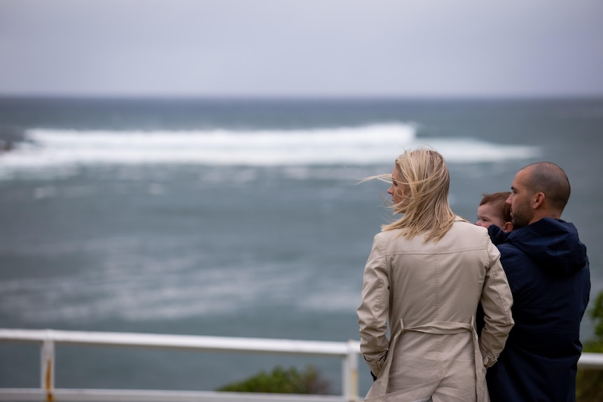 a family of three looking out to the waves and ocean