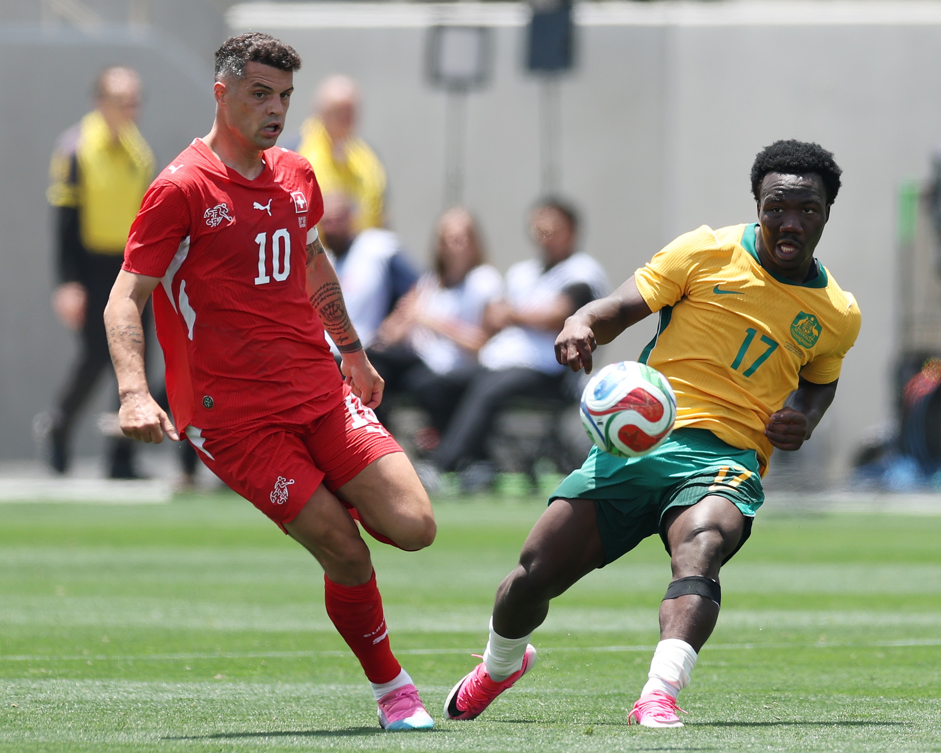 Nestory Irankunda, da Austrália, compete pela bola contra Granit Xhaka, da Suíça.