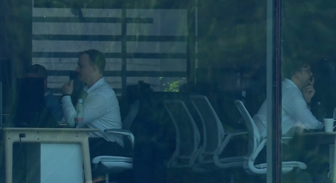 Two office workers sit in an office while at their computers