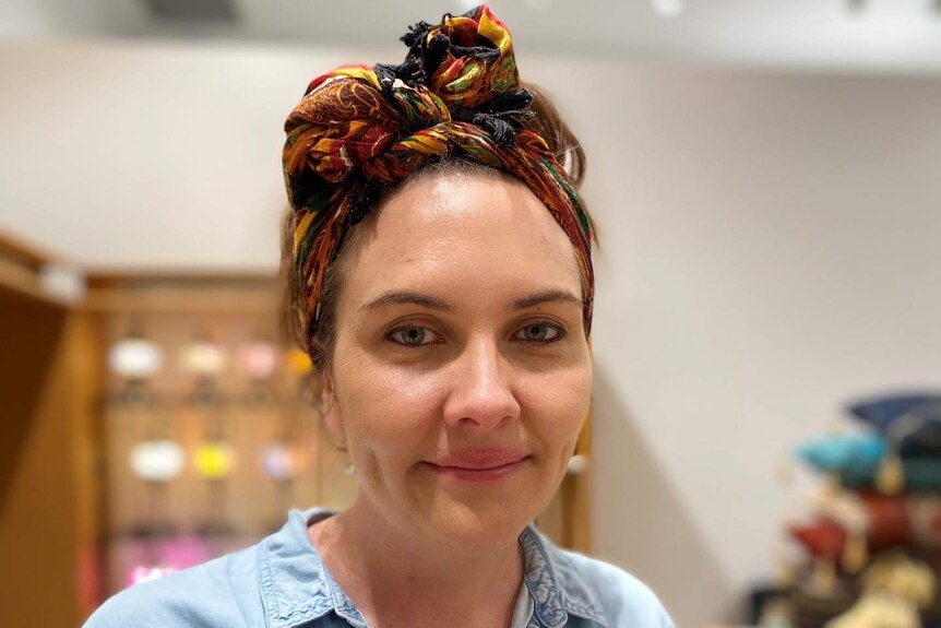 Sian Kocamis wearing a blue denim short sleeve shirt and a colourful headband in a store.
