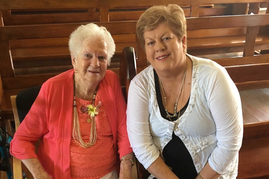 Marie McLean and her daughter Kaye Campbell sitting together in the front pew of an empty church