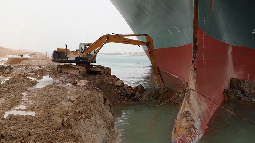 A backhoe is trying to dig out a giant ship that has run aground, the ship is approx 5x as big as the backhoe