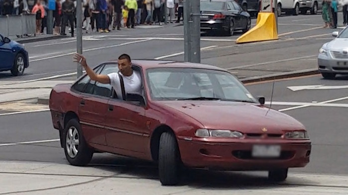 James Gargasoulas leans out the window of his maroon car as he does a burnout.