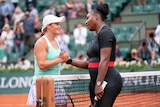 Ash Barty smiles at Serena Williams as they talk and shake hands at the net after a match at the French Open.