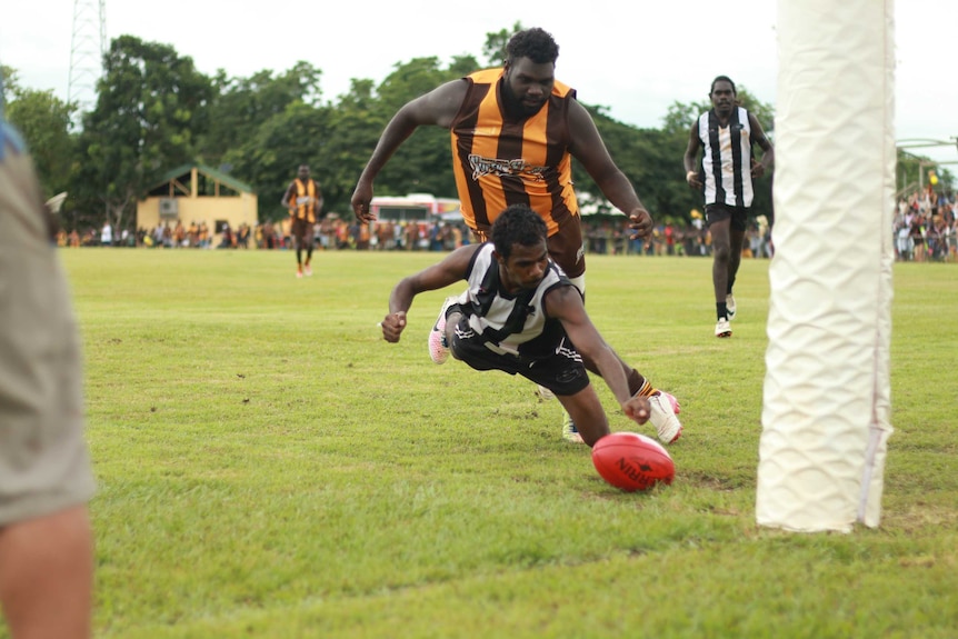 A Magpies player dives for the ball with a Superstars player close behind them.