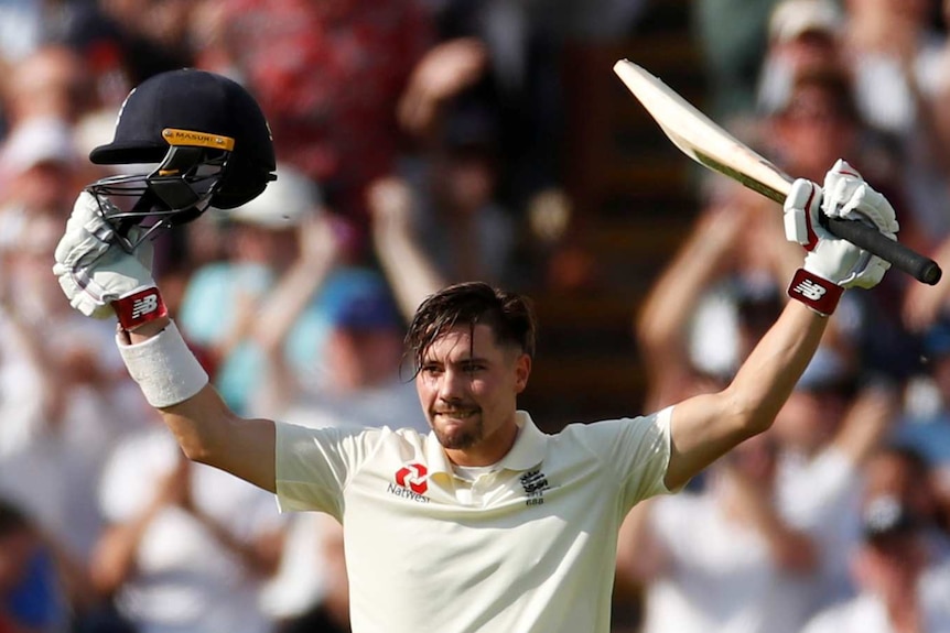 England batsman Rory Burns raises his bat and helmet into the sky in celebration.