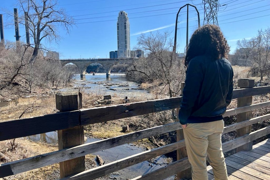 A man stands on a bridge.