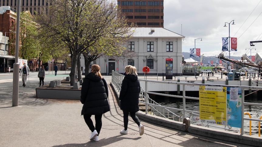 Mask-wearing pedestrians walk past the docks.